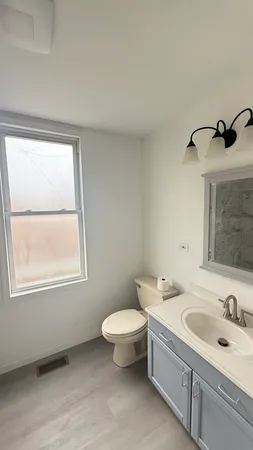 a bathroom with a granite countertop sink toilet a mirror and window