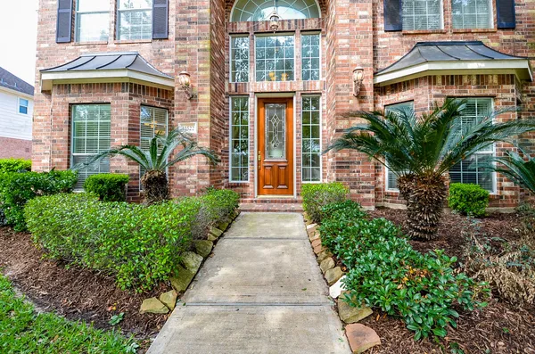 a front view of a brick house with a yard and potted plants