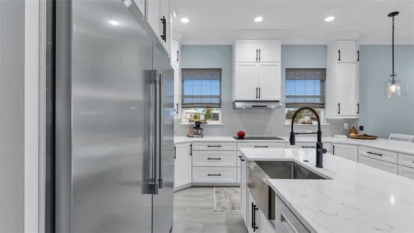 a kitchen with kitchen island white cabinets and refrigerator
