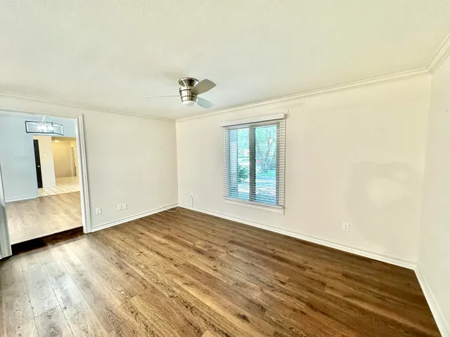 a view of an empty room with a window and wooden floor