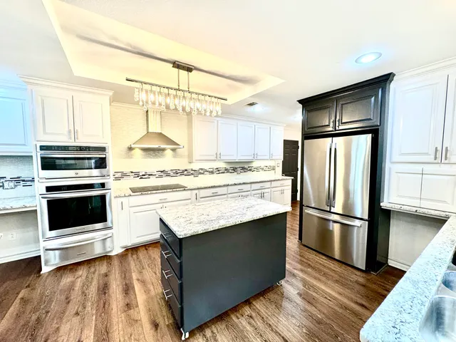 a kitchen with granite countertop a refrigerator stove and sink