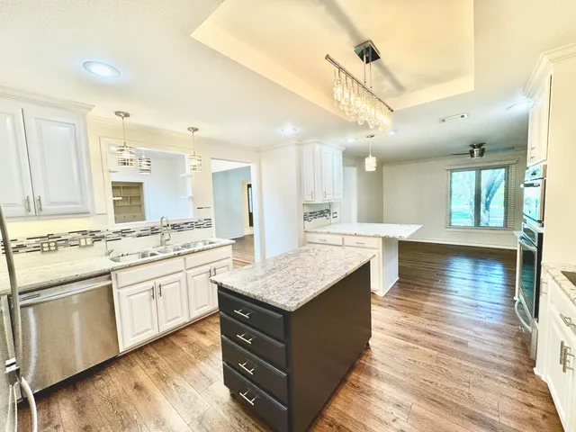 a kitchen with stainless steel appliances granite countertop a sink stove and wooden floor