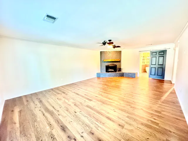 a view of empty room with fireplace and wooden floor