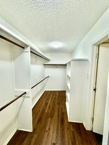 a view of walk in closet with wooden floor