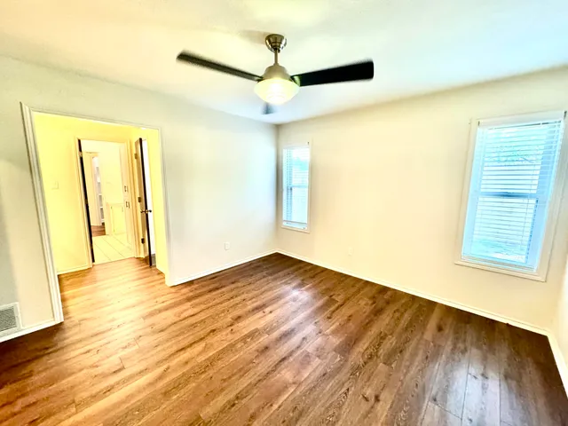 a view of empty room with wooden floor and fan