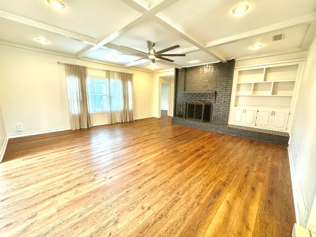 a view of empty room with wooden floor and fireplace
