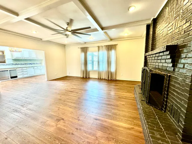 a view of an empty room with wooden floor and a fireplace
