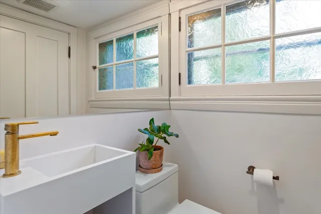 a bathroom with a sink a mirror a window and a shower