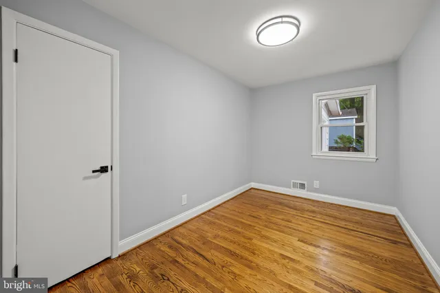an empty room with wooden floor and window