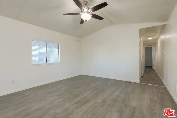 an empty room with wooden floor ceiling fan and windows