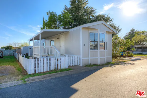 a view of a wooden house with a yard and fence