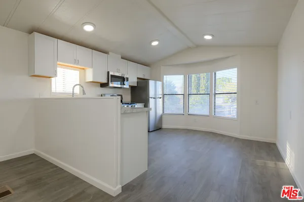a kitchen with a refrigerator a stove a microwave and a window