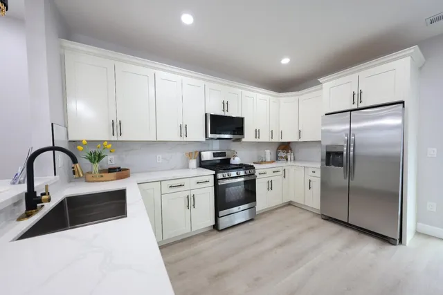 a kitchen with stainless steel appliances granite countertop a refrigerator sink and white cabinets