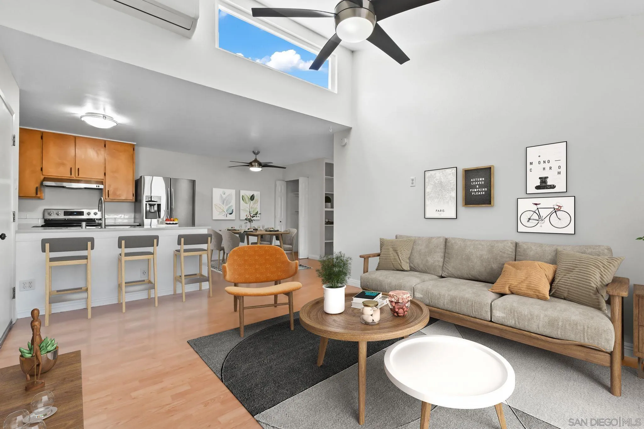 a living room with furniture kitchen view and a wooden floor
