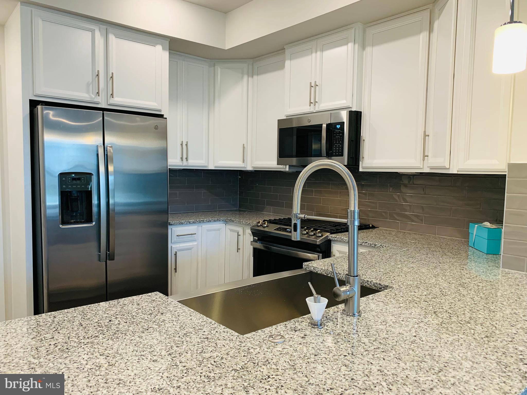 12884 Sunrise Ridge Alley, Unit 47 Herndon, VA 20171 - Photo 7 of 37 a kitchen with stainless steel appliances granite countertop a refrigerator a stove a sink and white cabinets