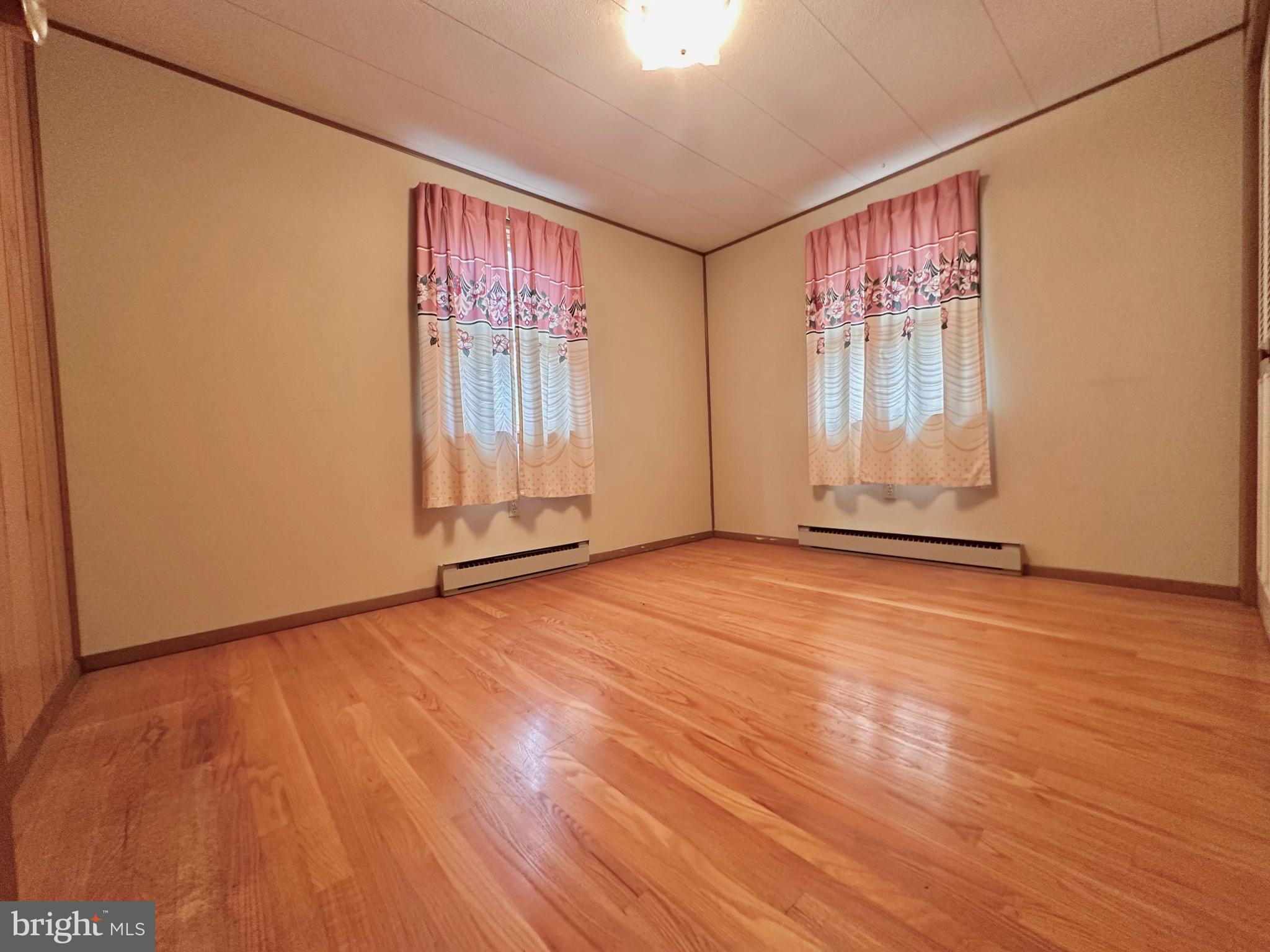 242 Gracey Road Waterfall, PA 16689 - Photo 15 of 40 an empty room with wooden floor and windows with curtains