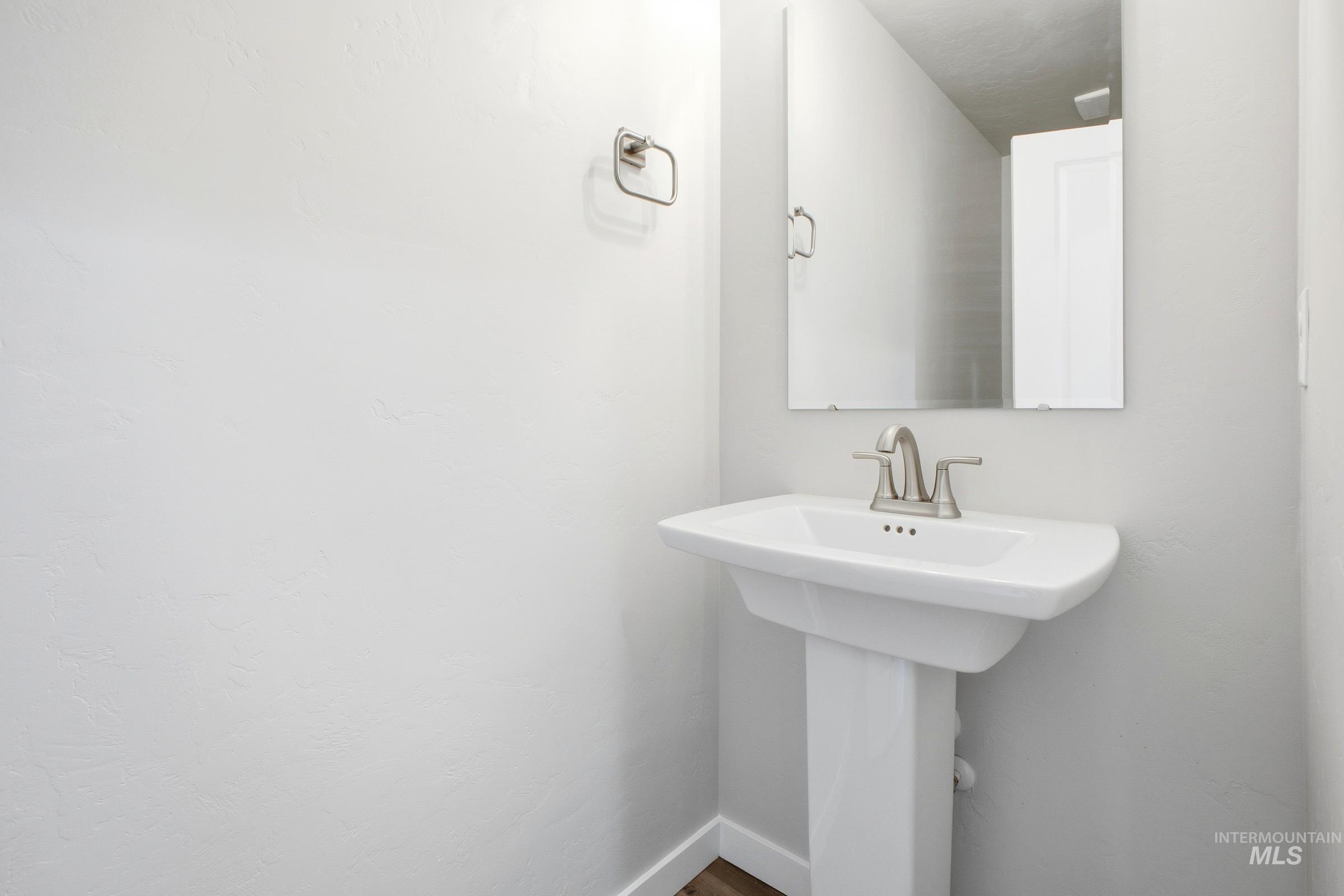 13325 Scrape Street Caldwell, ID 83607 - Photo 12 of 24 Clean and bright powder room featuring a white pedestal sink with chrome faucet, mirrored medicine cabinet, and crisp white walls throughout