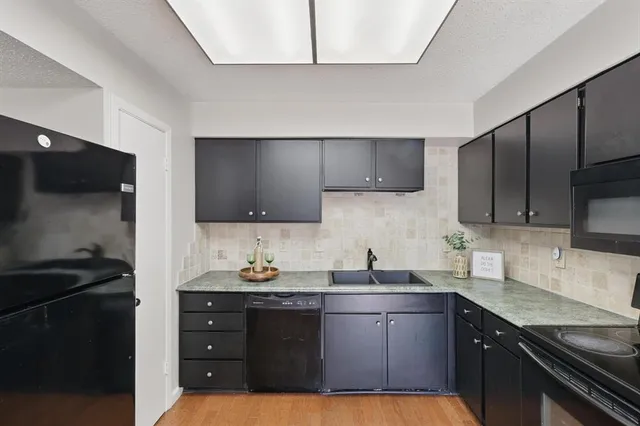 a kitchen with granite countertop a sink stove and refrigerator