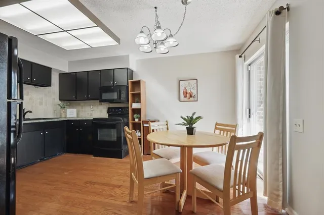 a kitchen with stainless steel appliances granite countertop a dining table chairs a refrigerator and a microwave