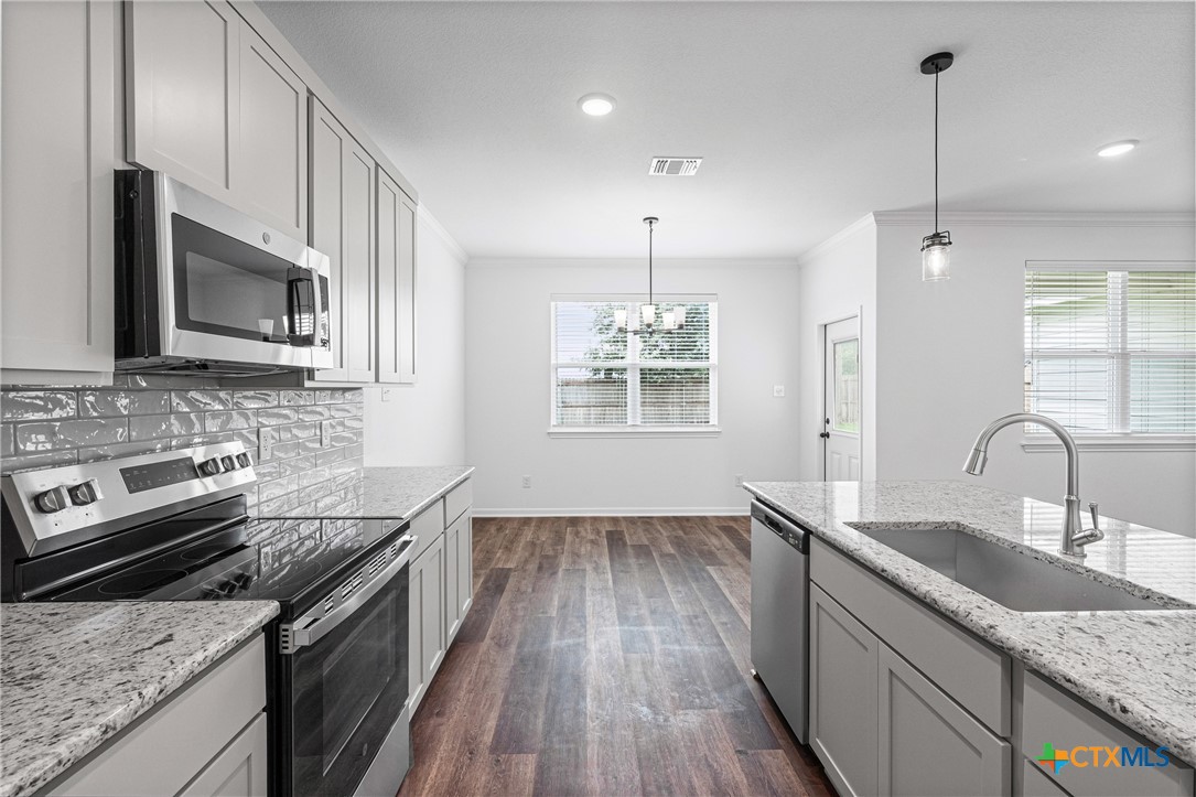 8023 Pineridge Way Temple, TX 76502 - Photo 20 of 28 a kitchen with granite countertop stainless steel appliances cabinets a sink and a wooden floor