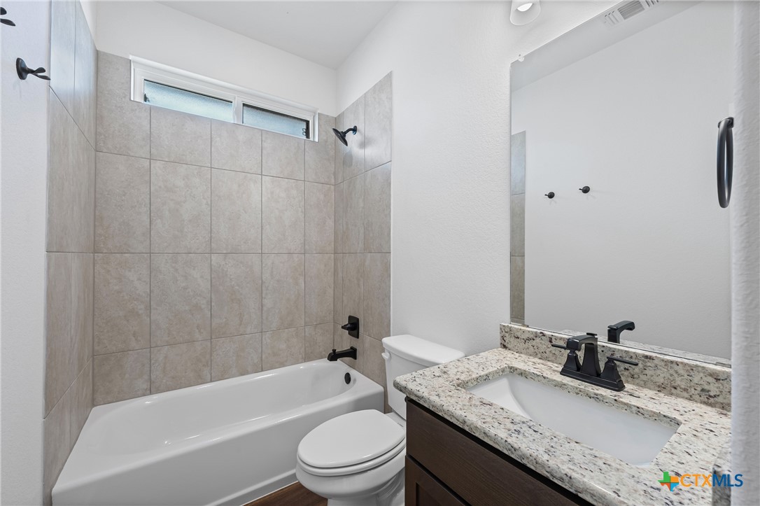 8023 Pineridge Way Temple, TX 76502 - Photo 8 of 28 a bathroom with a granite countertop bathtub shower sink vanity mirror and toilet