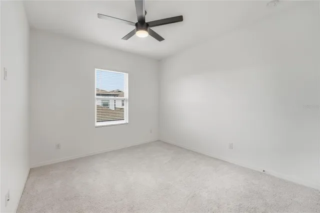 an empty room with a window and a fan