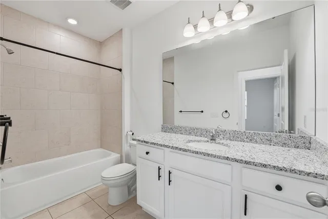 a bathroom with a granite countertop sink a toilet and bathtub