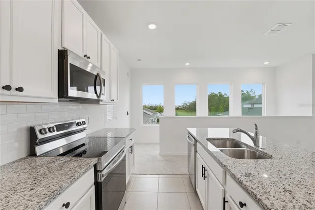 a kitchen with stainless steel appliances granite countertop a sink a stove and a microwave
