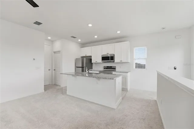 a view of kitchen with stainless steel appliances kitchen island sink and refrigerator