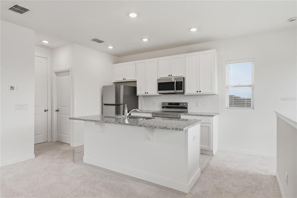 6552 Barnstorm Way St. Cloud, FL 34771 - Photo 7 of 17 a kitchen with stainless steel appliances granite countertop a sink and a stove