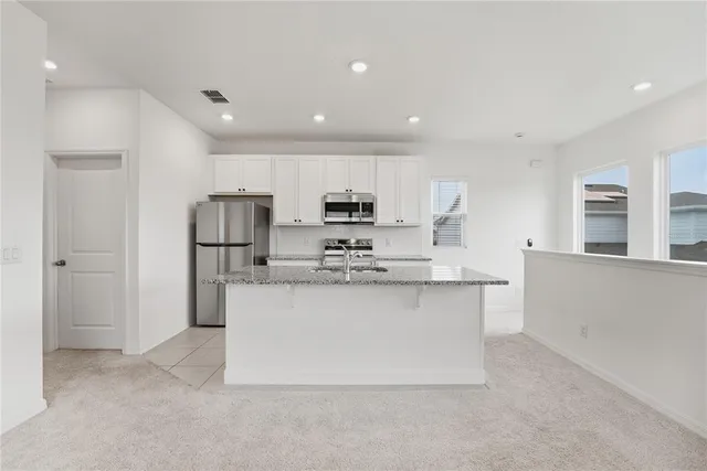 a kitchen with stainless steel appliances granite countertop a refrigerator a stove and a sink