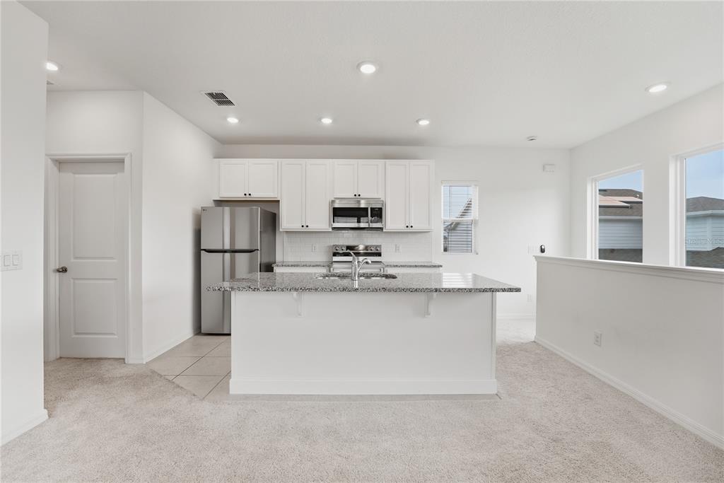 6552 Barnstorm Way St. Cloud, FL 34771 - Photo 8 of 17 a kitchen with stainless steel appliances granite countertop a refrigerator a stove and a sink