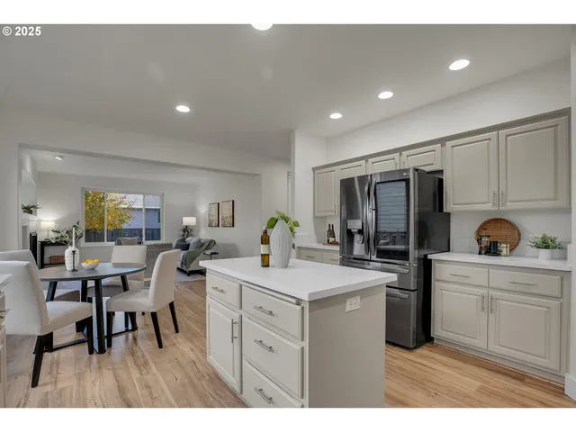 a kitchen with a sink dishwasher a dining table and chairs with wooden floor