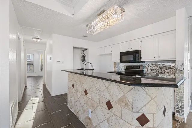 a kitchen with stainless steel appliances a sink a stove a microwave a refrigerator a white cabinets and couches