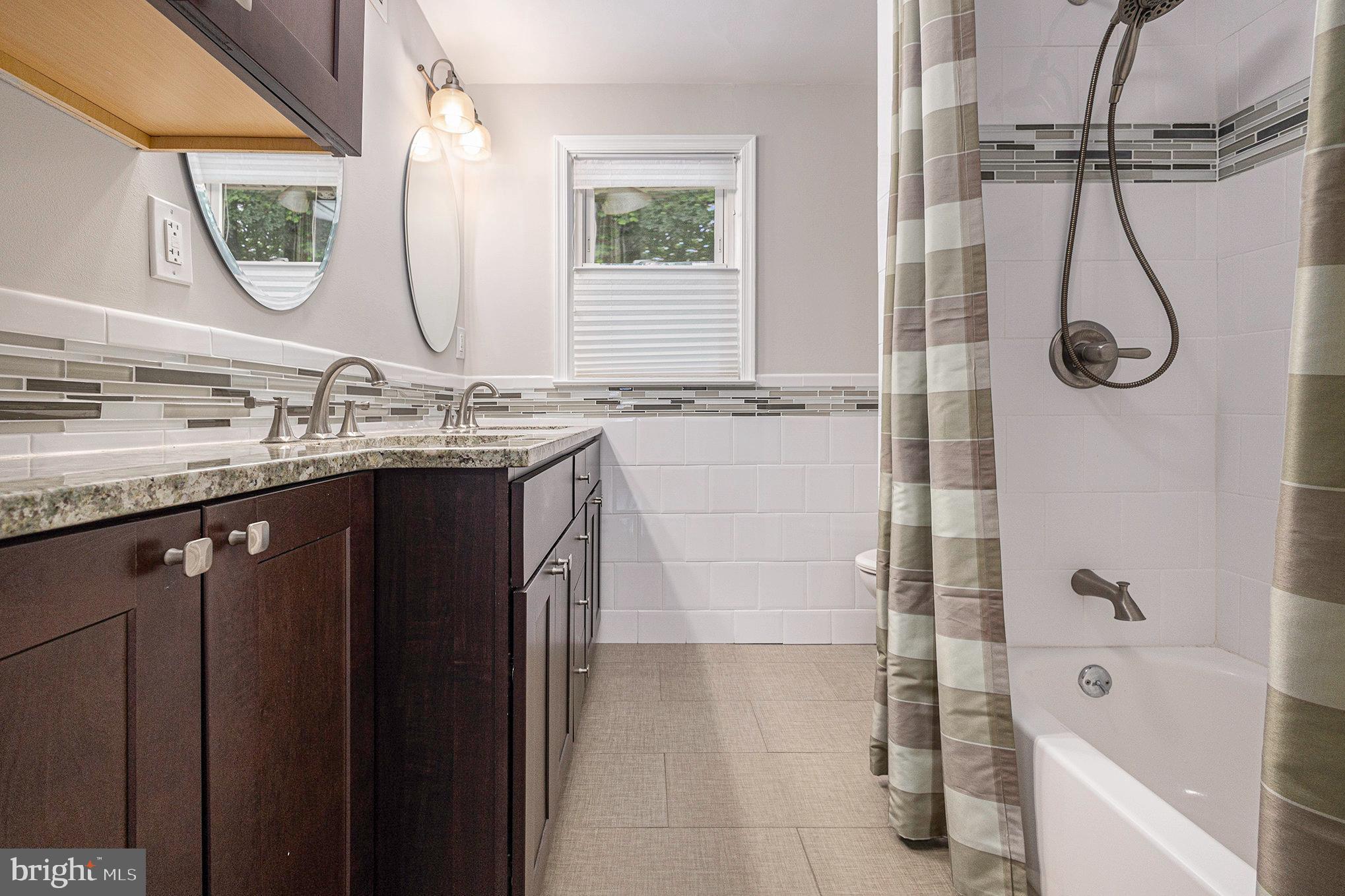 556 Forest Road Wayne, PA 19087 - Photo 13 of 35 a bathroom with a granite countertop sink a mirror and a bathtub
