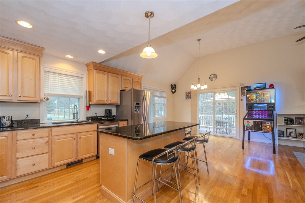 a kitchen with stainless steel appliances kitchen island granite countertop a stove a refrigerator a sink dishwasher and white cabinets with wooden floor