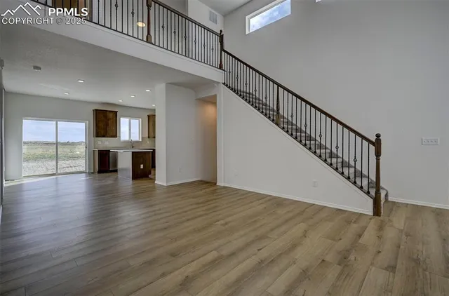 a view of a livingroom with wooden floor and a kitchen space