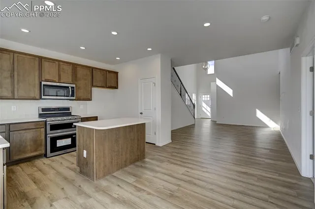 a kitchen with stainless steel appliances granite countertop a refrigerator a stove microwave and a sink