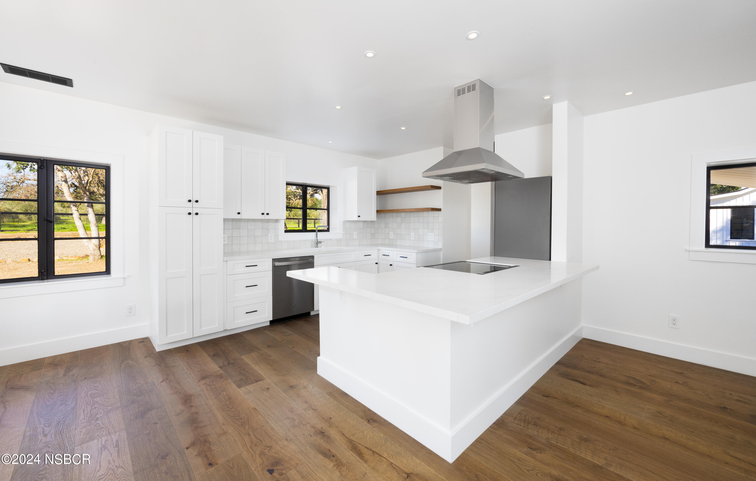 2380 North Refugio Road Santa Ynez, CA 93460 - Photo 11 of 38 a large white kitchen with wooden floors and appliances