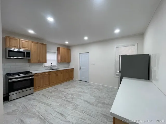 a kitchen with stainless steel appliances granite countertop a stove a sink and a refrigerator