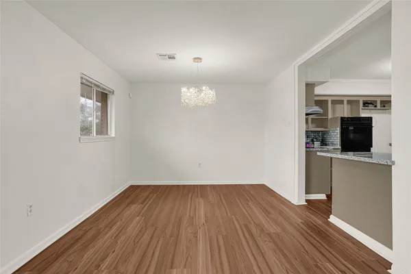 an empty room with wooden floor fireplace and windows