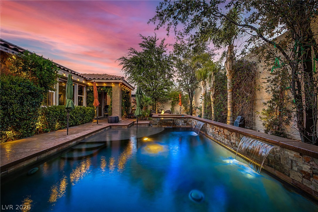 7415 Campbell Ranch Avenue Las Vegas, NV 89179 - Photo 46 of 52 An inviting backyard oasis offers a sparkling pool with water features under a vibrant sunset sky.
