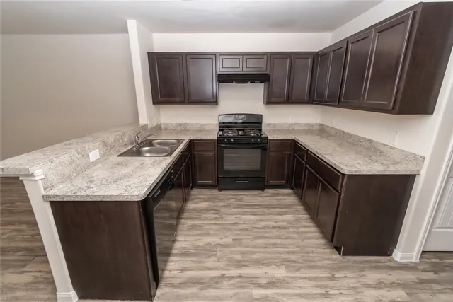 a kitchen with granite countertop a sink stove and cabinets
