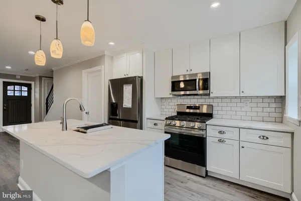 a kitchen with kitchen island granite countertop stainless steel appliances a stove cabinets and wooden floor