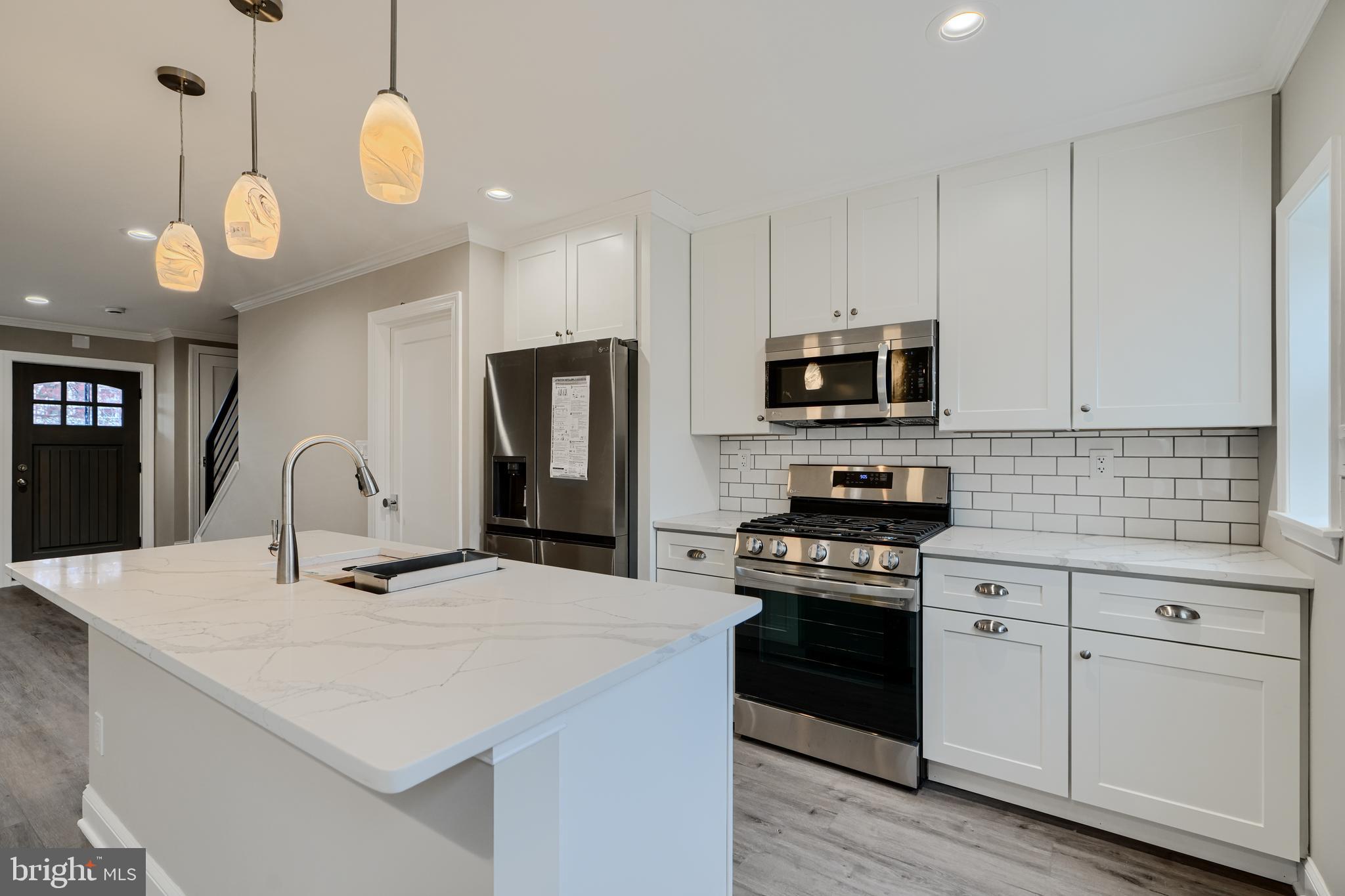621 Ponca Street Baltimore, MD 21224 - Photo 1 of 38 a kitchen with kitchen island granite countertop stainless steel appliances a stove cabinets and wooden floor