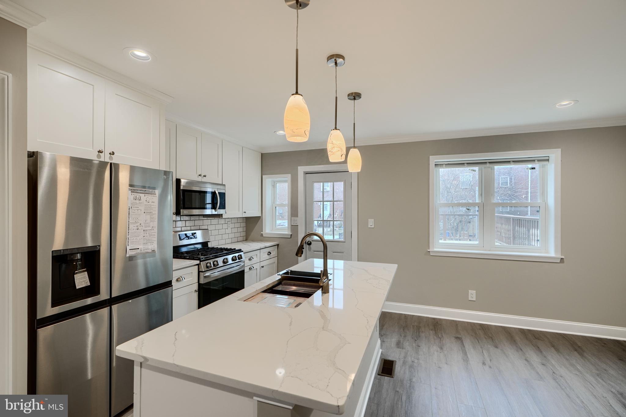 621 Ponca Street Baltimore, MD 21224 - Photo 11 of 38 a kitchen with stainless steel appliances granite countertop a refrigerator a stove top oven a sink dishwasher a refrigerator white cabinets and wooden floor