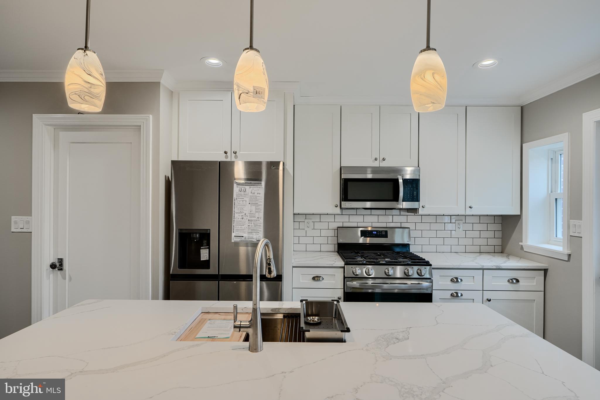 621 Ponca Street Baltimore, MD 21224 - Photo 10 of 38 a kitchen with stainless steel appliances kitchen island granite countertop a stove a sink and a refrigerator