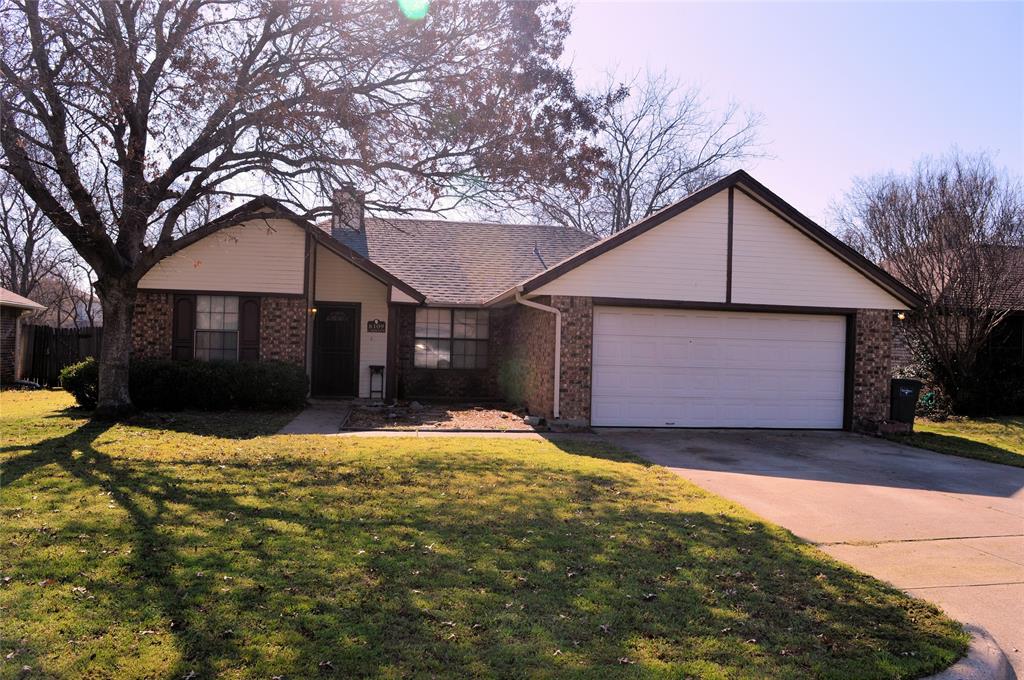 Single story home featuring brick siding, a garage, driveway, a front lawn, and a chimney