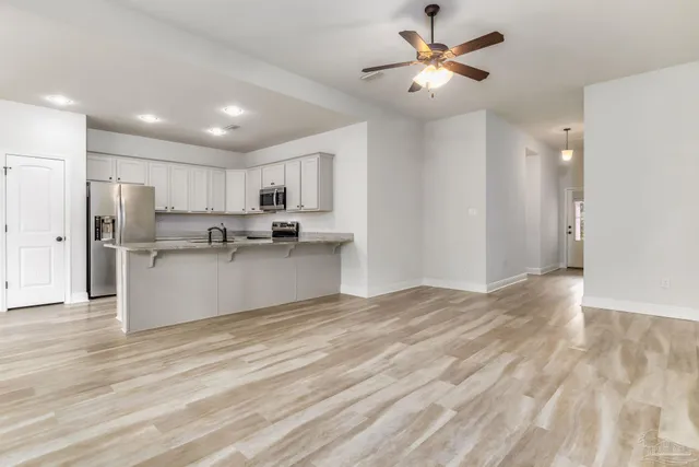 a view of an empty room with a chandelier fan