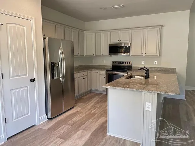 a kitchen with stainless steel appliances granite countertop a refrigerator microwave and sink